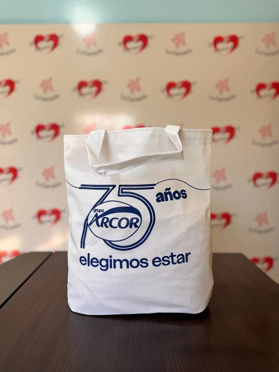 Bolsa de friselina rosa con asas de cinta gris y diseño floral impreso