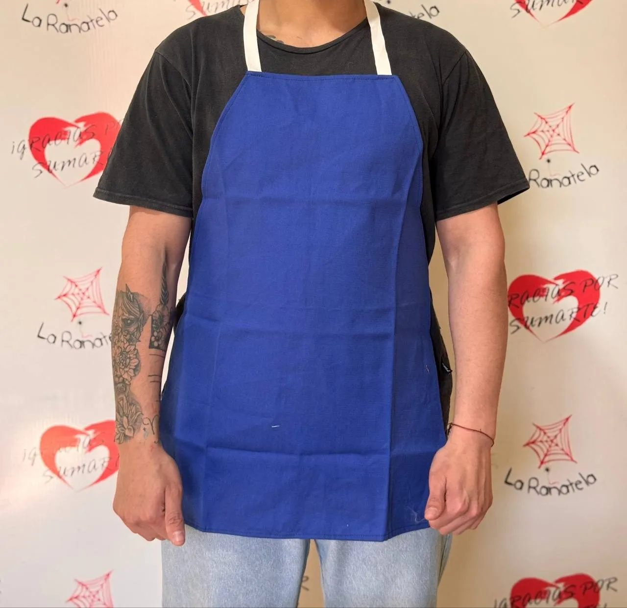 Delantal de cocina azul con peto y tiras blancas, puesto sobre una remera oscura
