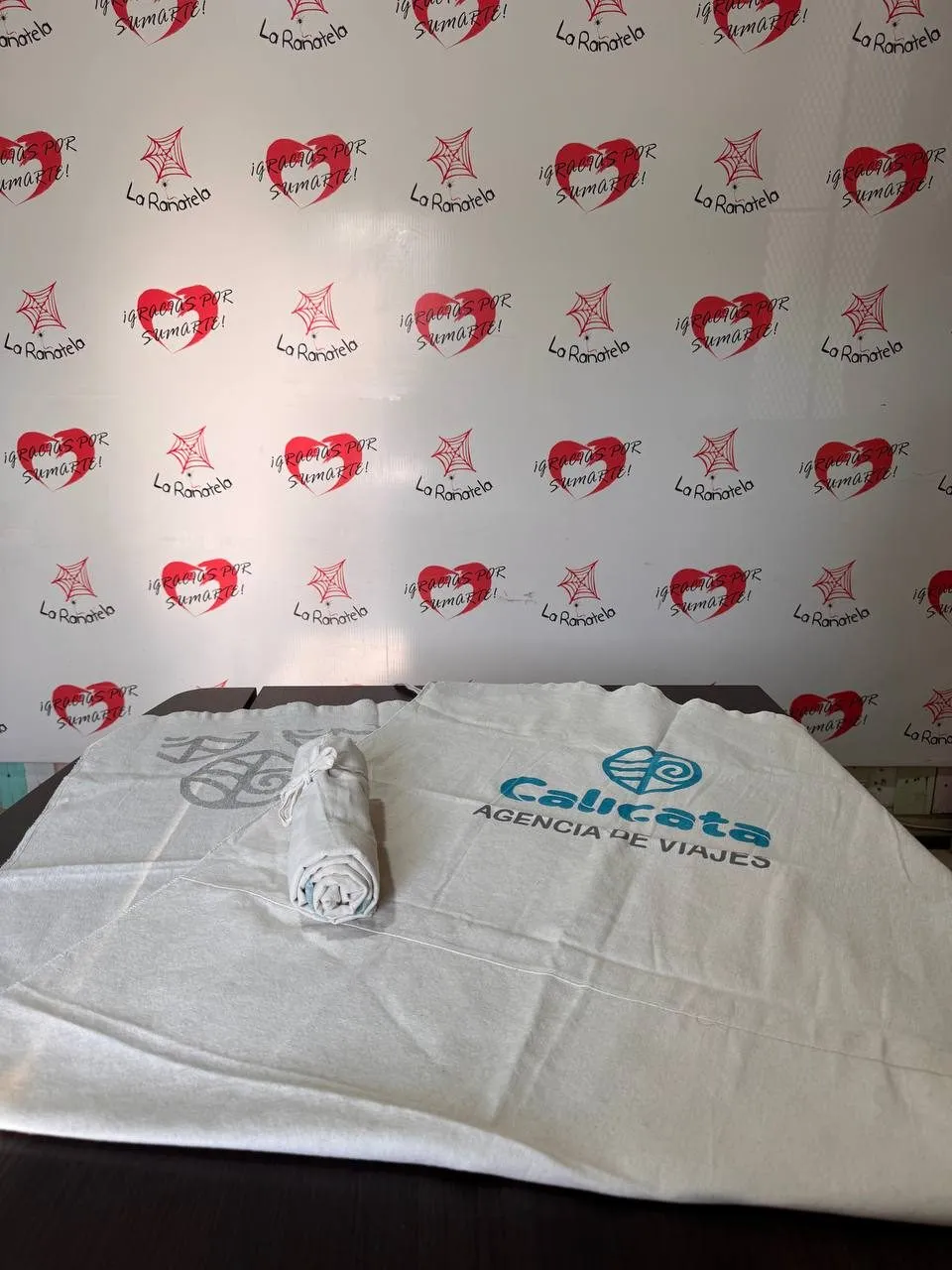 Dos lonas playeras de algodón crudo con logos estampados, una enrollada