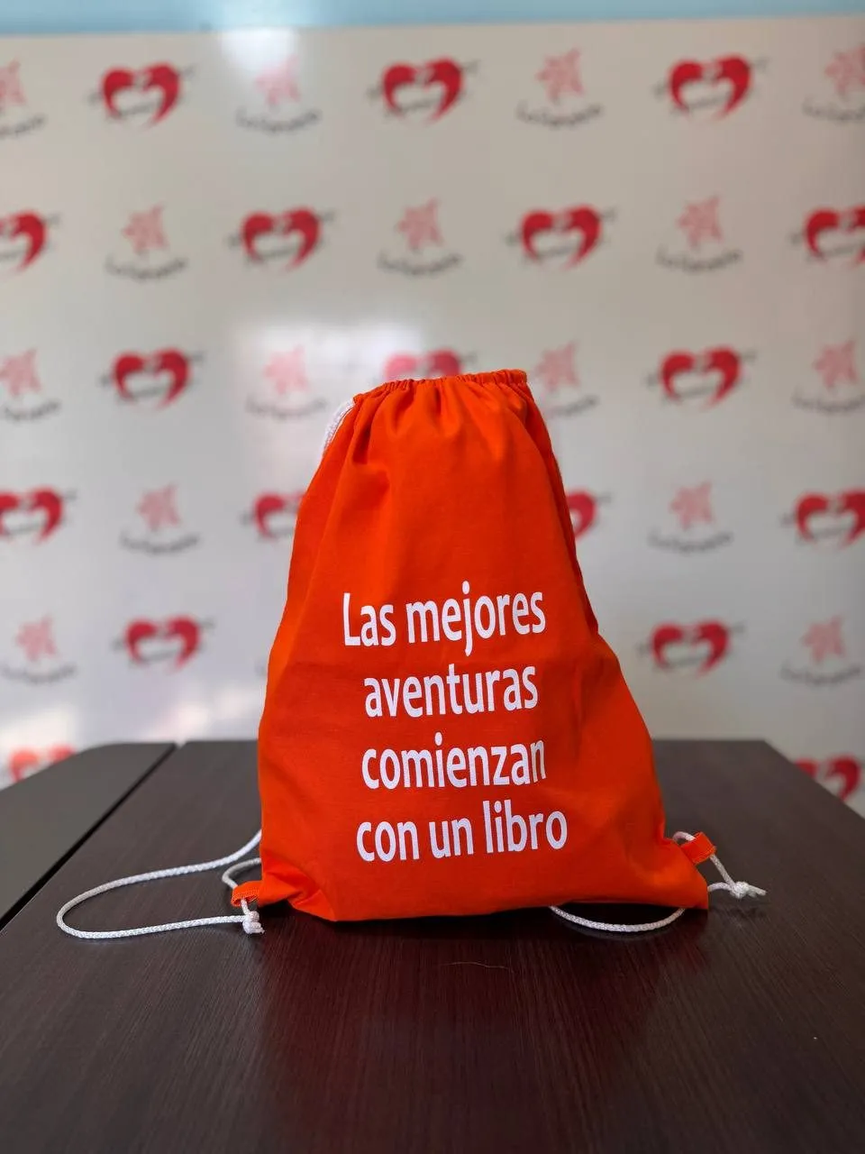 Mochila tipo tula de gabardina naranja con cordones blancos y texto impreso