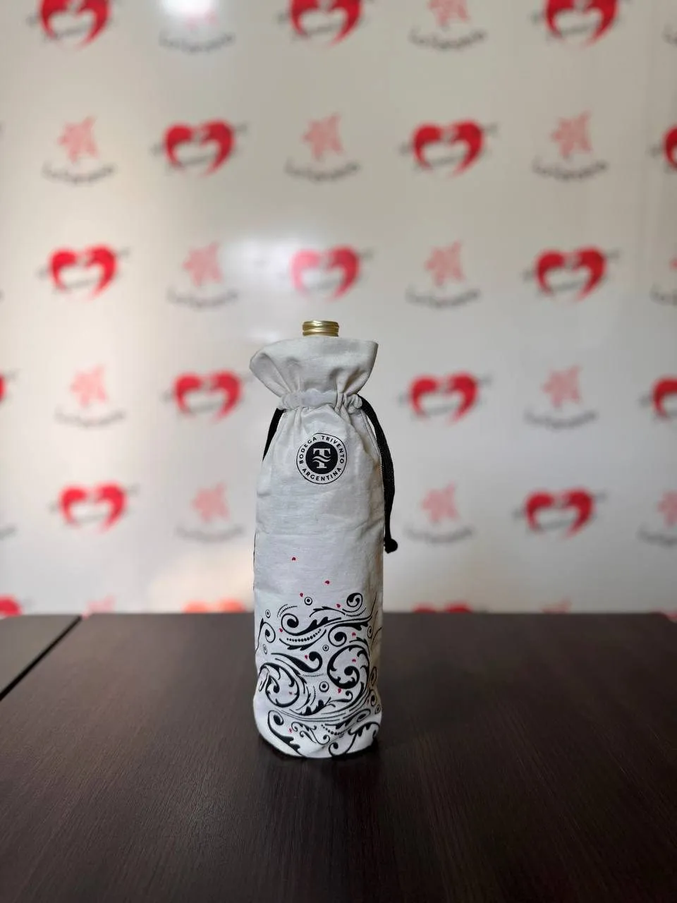 Funda de lienzo blanco con cordón negro cubriendo una botella de vino