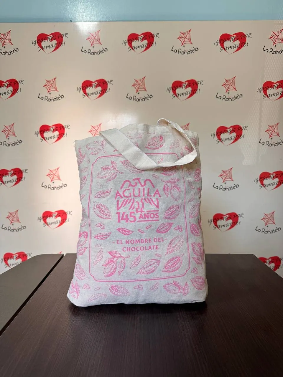 Bolsa de lienzo natural con asas del mismo material y logo impreso en el frente